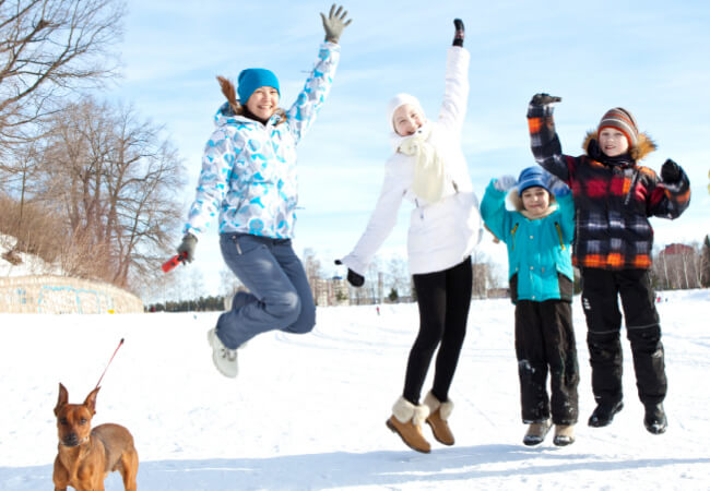 family happily jumping in the snow
